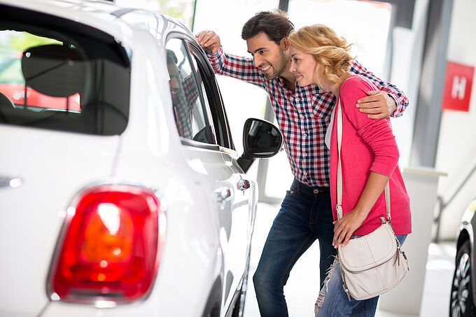 Young  couple chooses to buy a car in car dealership saloon Young  couple chooses to buy a car in car dealership saloon